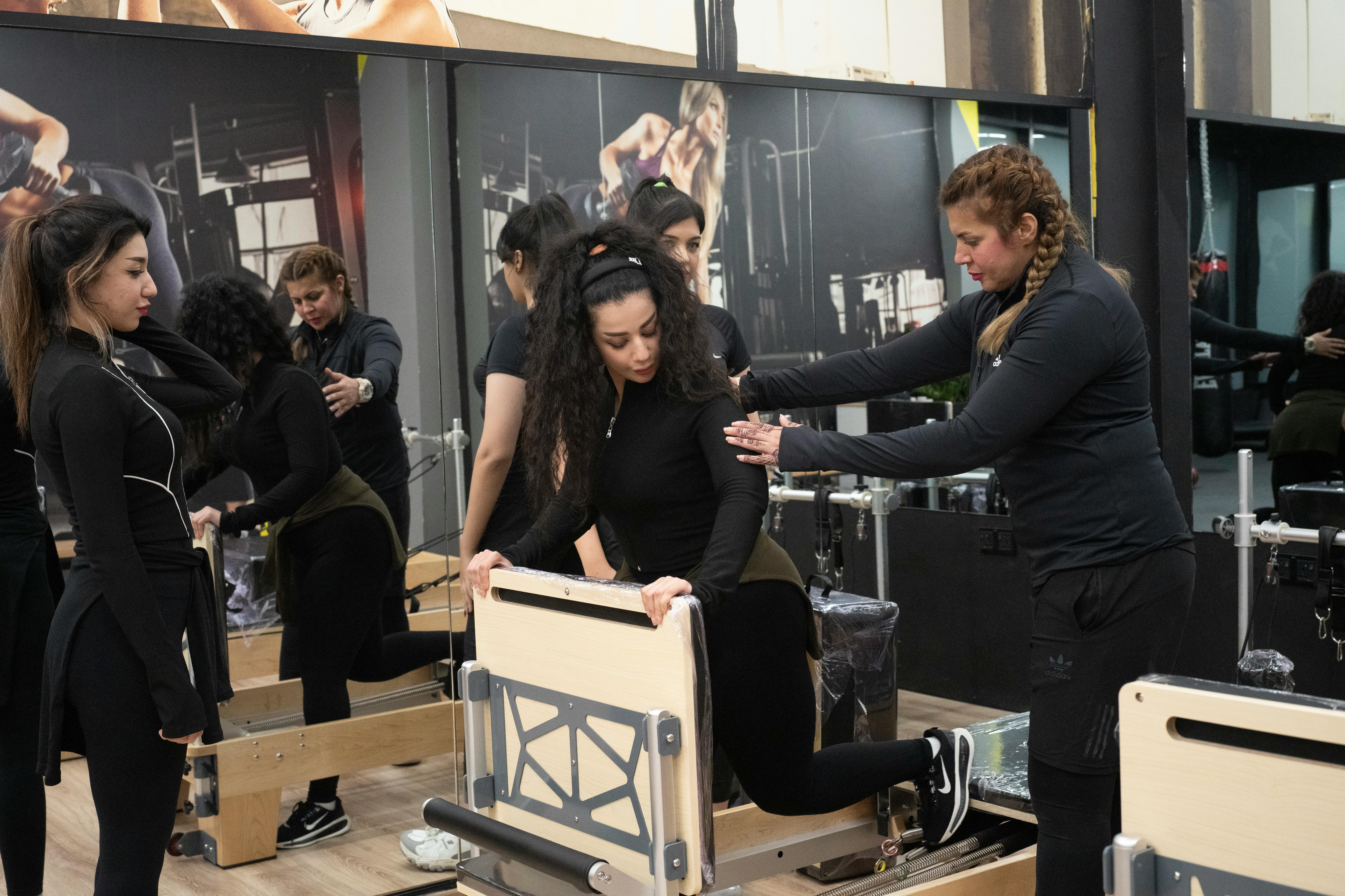 Instructor coaching clients on reformer machines in a studio